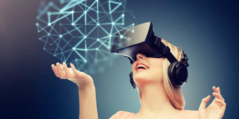 technology, augmented reality, entertainment and people concept - happy young woman with virtual headset or 3d glasses over dark blue background and low poly projection