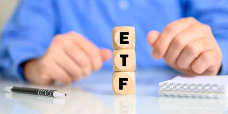 Wooden cubes with the letters making the word ETF with a man in the background